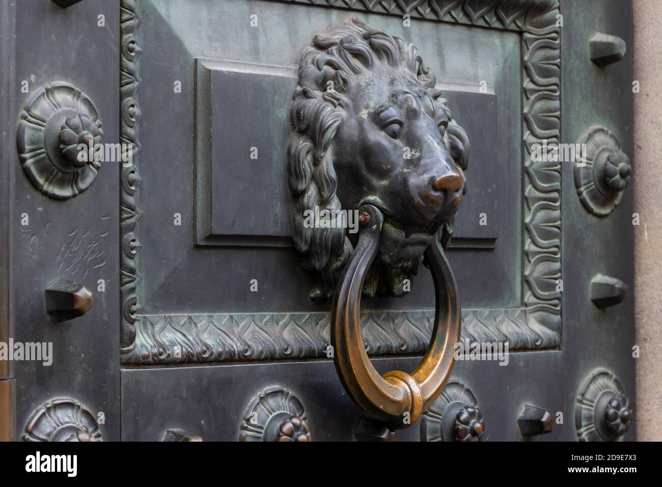 Antico anello di pomolo in bronzo della porta a forma di leone su una vecchia porta. Foto Stock