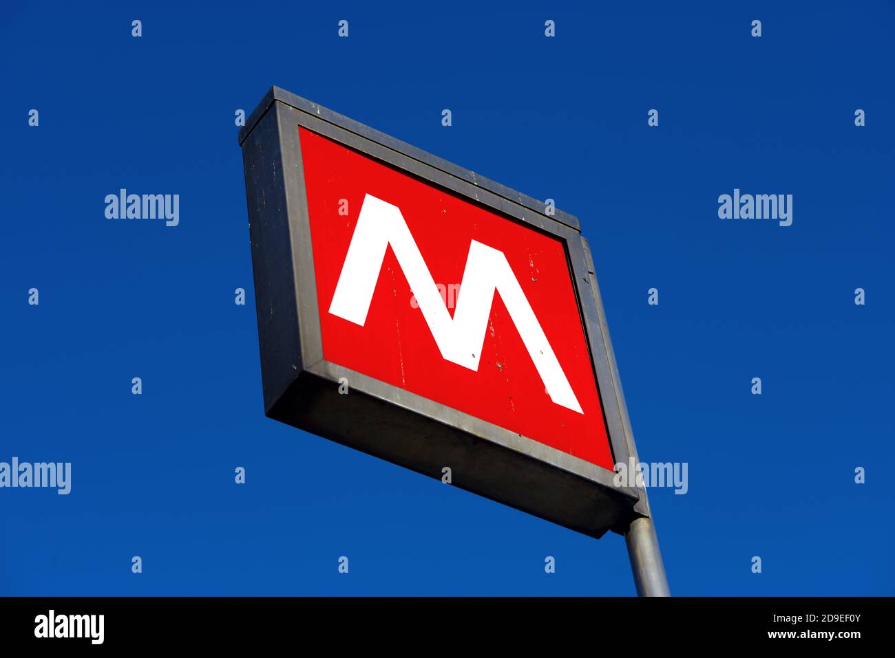 Segno rosso della metropolitana con cielo blu, nel centro di Milano. Foto Stock
