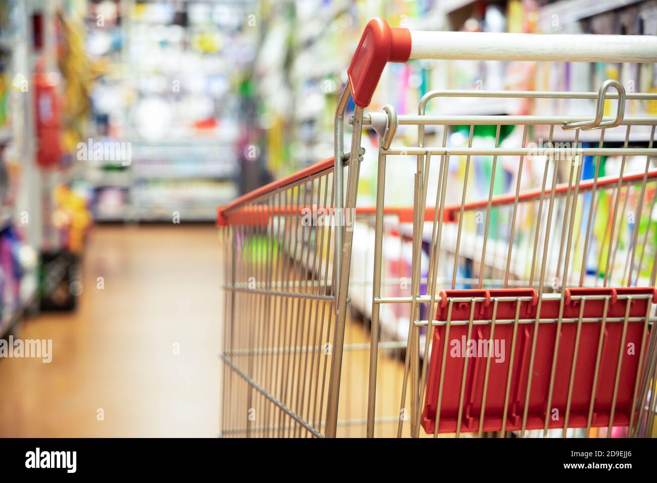 Carrello carrello di shopping contro corridoio supermercato sfondo offuscato Foto Stock