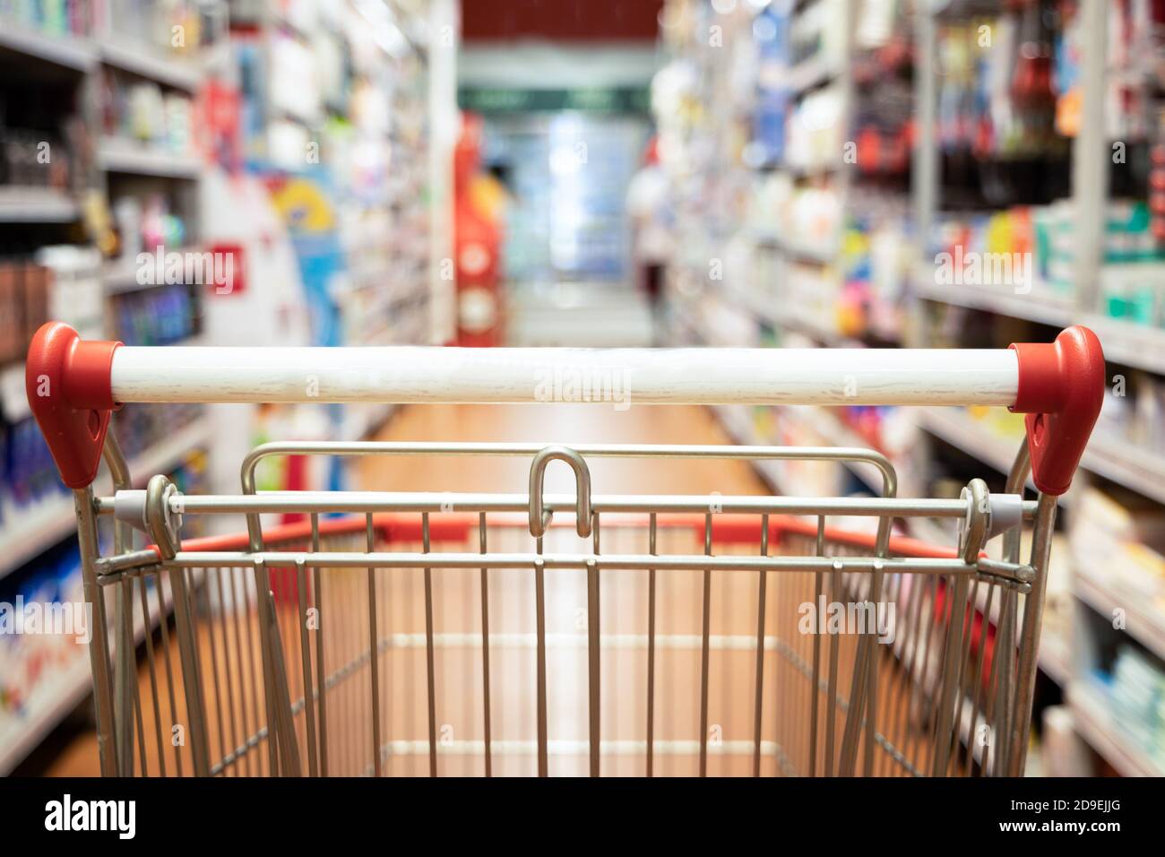 Vista prospettica carrello carrello carrello con corridoio supermercato sfondo sfocato Foto Stock