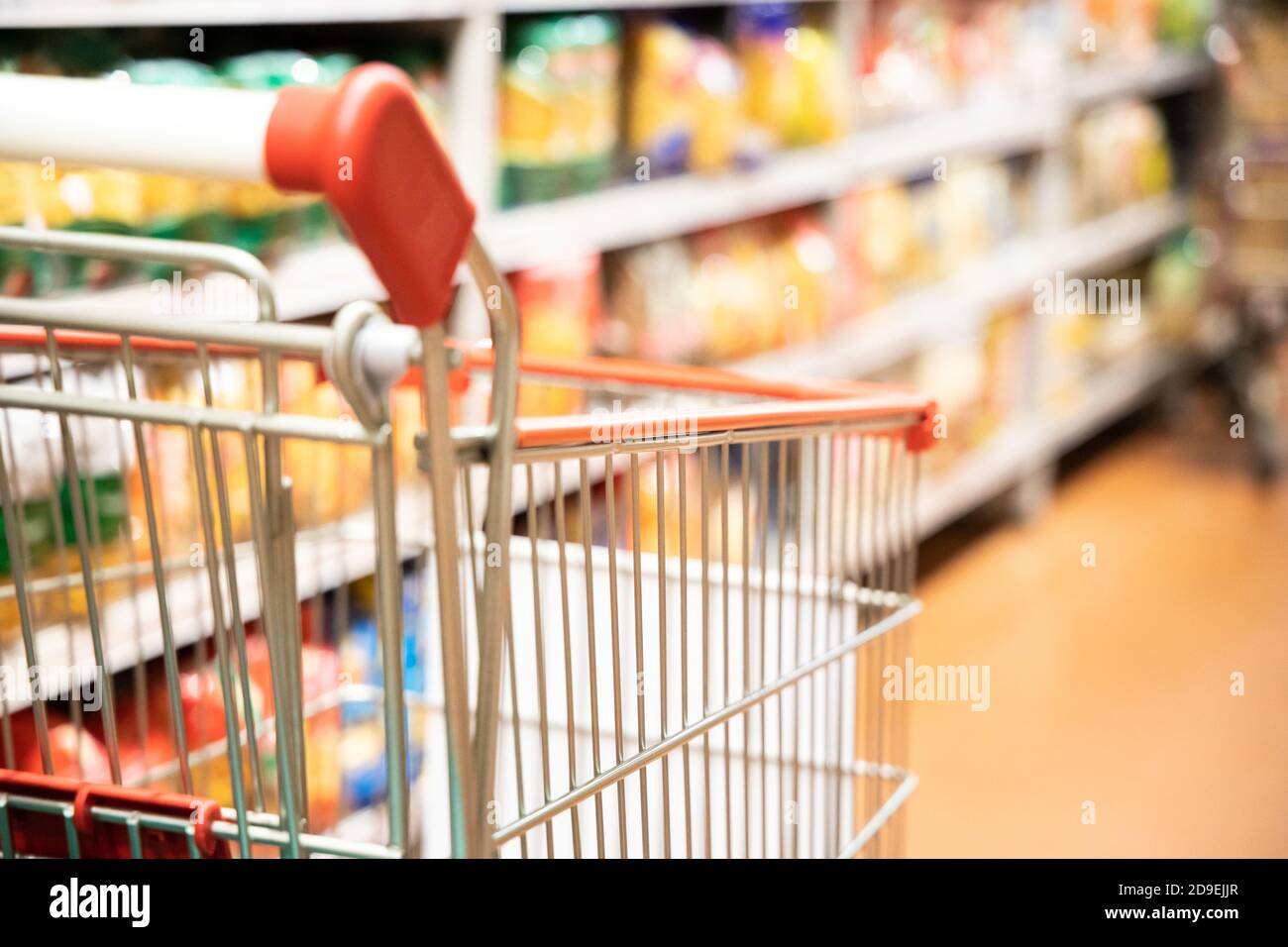Carrello del carrello di shopping con DOF poco profondo contro lo sfondo della corsia del supermercato Foto Stock