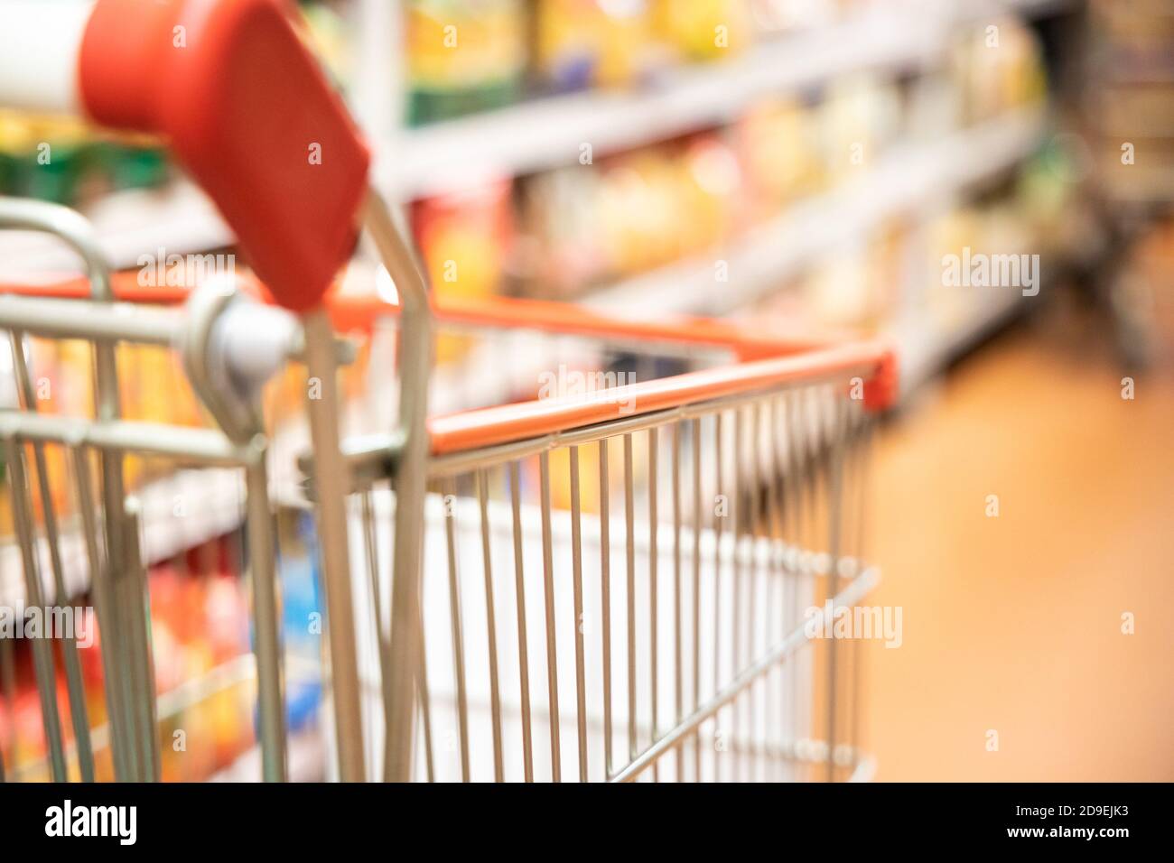 Carrello del carrello di shopping con DOF poco profondo contro lo sfondo della corsia del supermercato Foto Stock