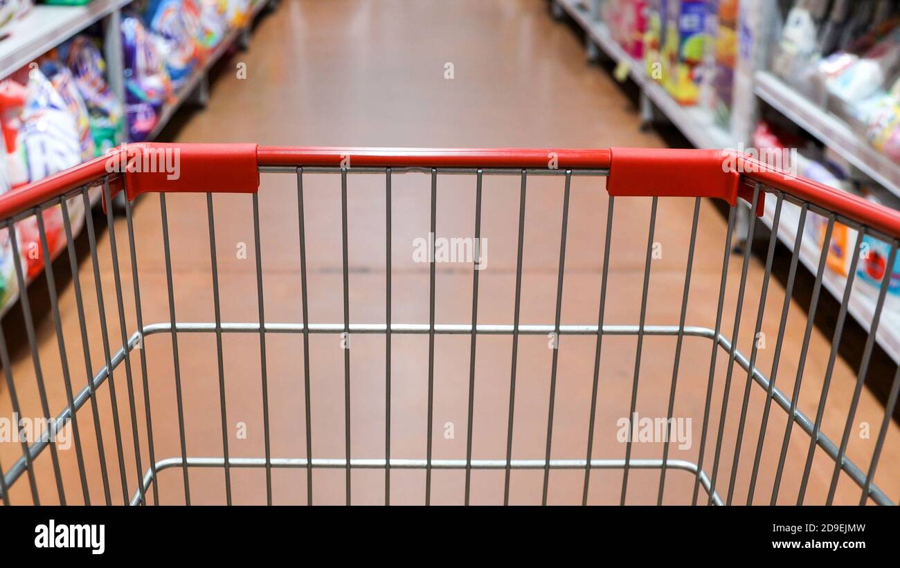 Vista prospettica carrello carrello carrello con corridoio supermercato sfondo sfocato Foto Stock