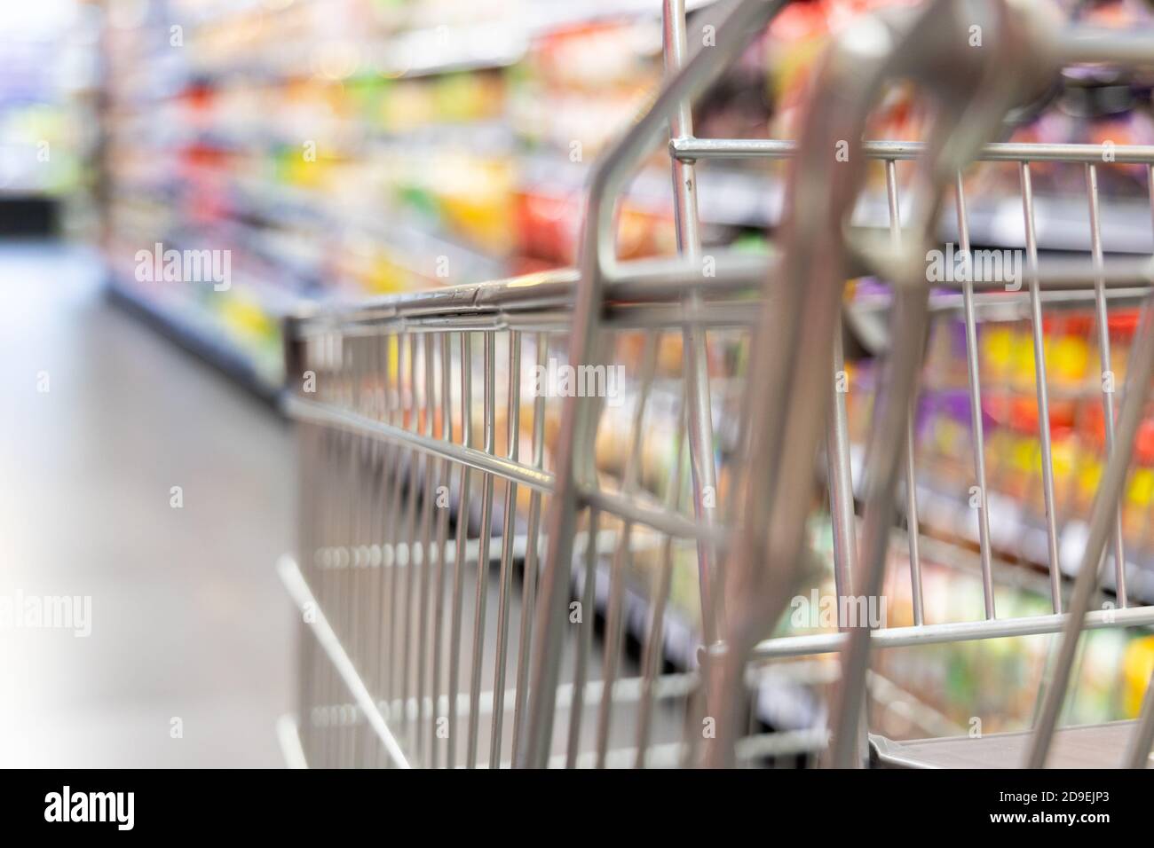 Carrello del carrello di shopping con DOF poco profondo contro lo sfondo della corsia del supermercato Foto Stock