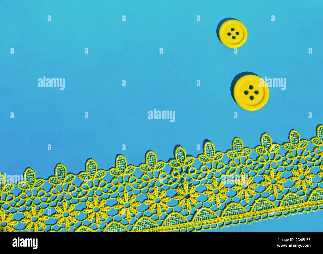 Su sfondo blu, due bottoni gialli e laccio giallo. Lavoro di ago. Accessori per cucire. Spazio di copia. Foto Stock