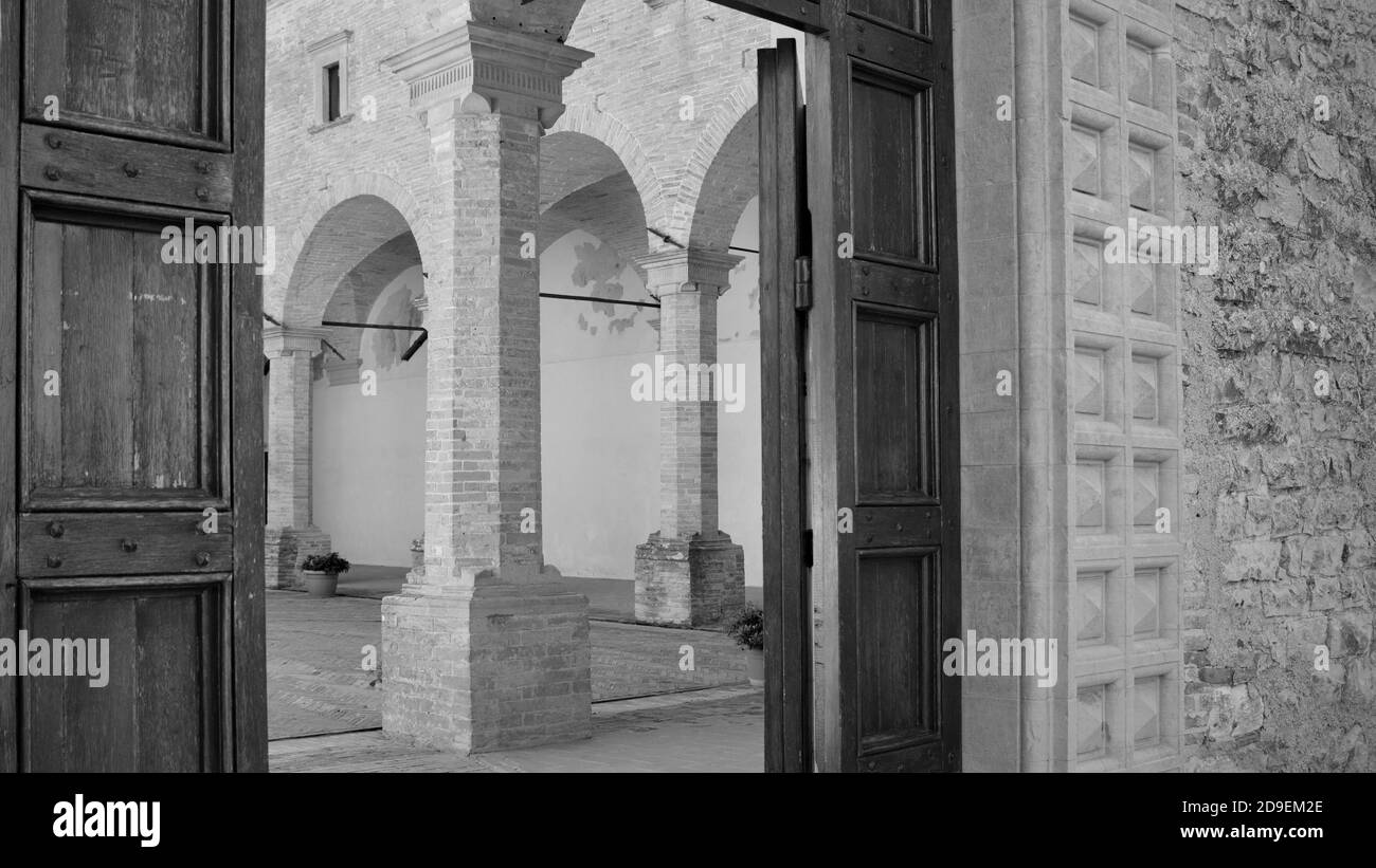 L'ingresso di un'abbazia medievale con porta in legno, colonne e archi in mattoni (Gubbio, Umbria, Italia) Foto Stock
