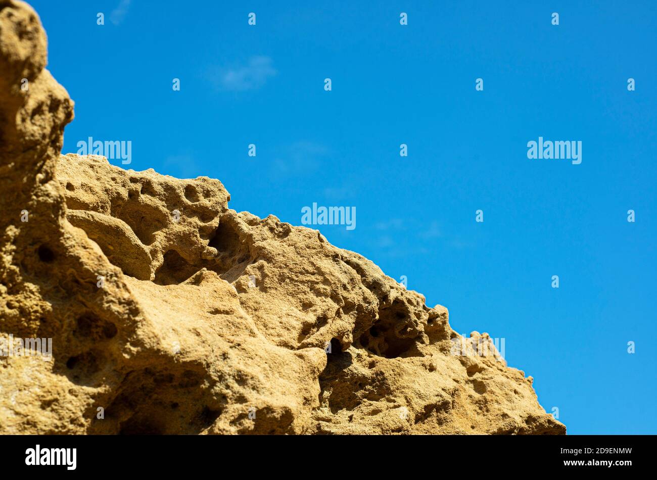 Texture rock su uno sfondo di cielo blu. La struttura perforata porosa della pietra. Rocce costiere. Foto Stock