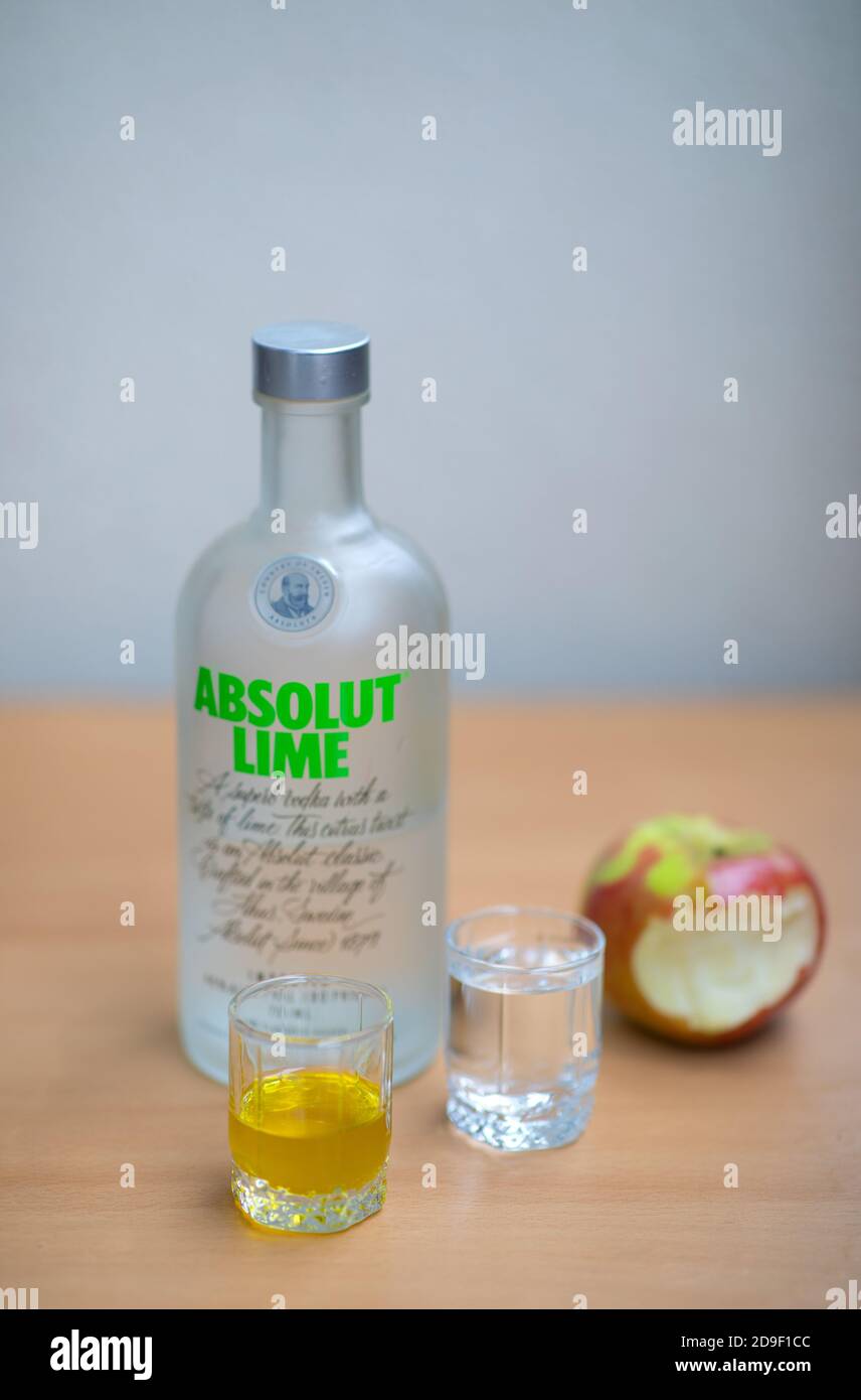 Una bottiglia di Absolut Vodka, un piccolo bicchiere di Absolut Vodka e olio e mela sul tavolo di legno. Varsavia, Polonia. 05.11.2020 Foto Stock