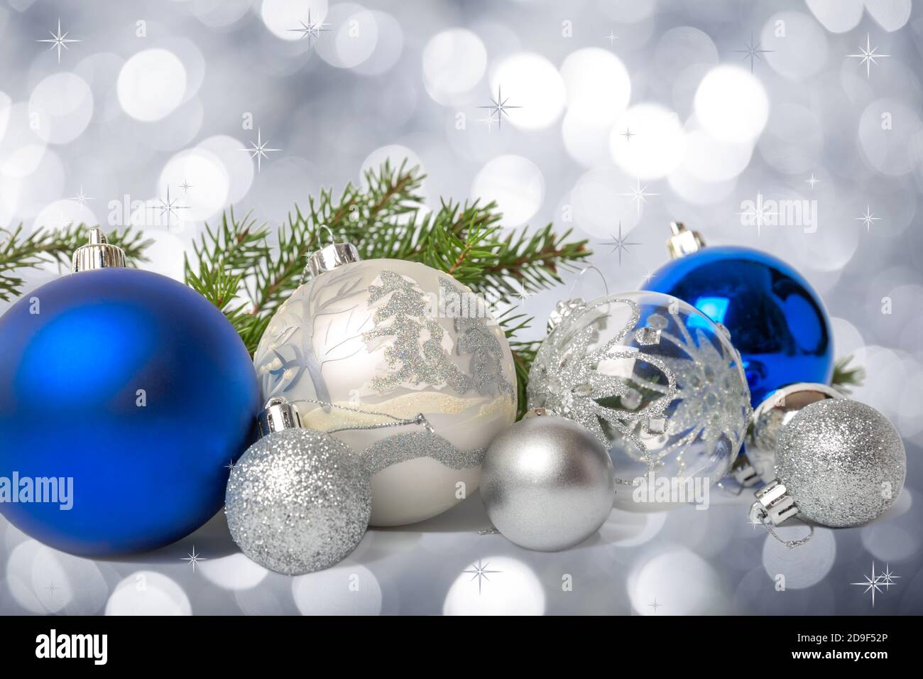 Gruppo di palle di Natale blu e argento e ramo di abete su sfondo argentato bokeh Foto Stock