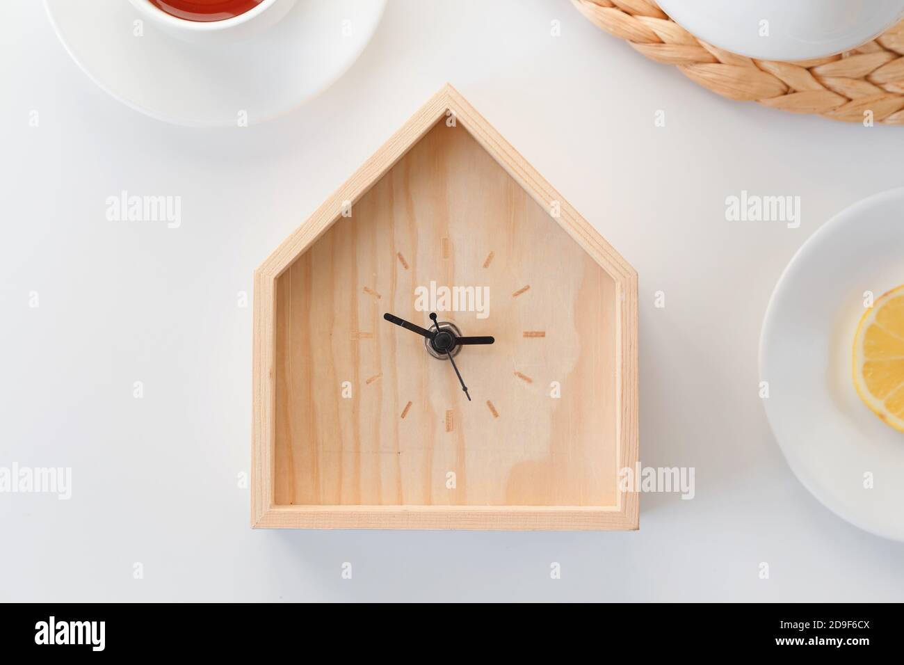 Orario cena. Orologio in legno a forma di casa isolato su sfondo bianco. Concetto minimo. Disposizione piatta. Vista dall'alto. Foto Stock