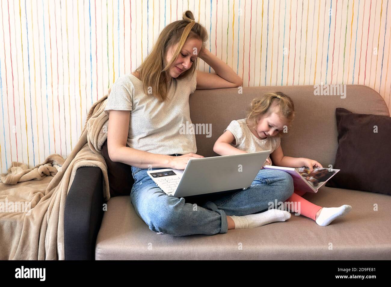 Madre che lavora da casa con i bambini. Quarantine covid-19 e chiuso la scuola durante l'epidemia di coronavirus. Homeschooling e lavoro freelance. Foto Stock