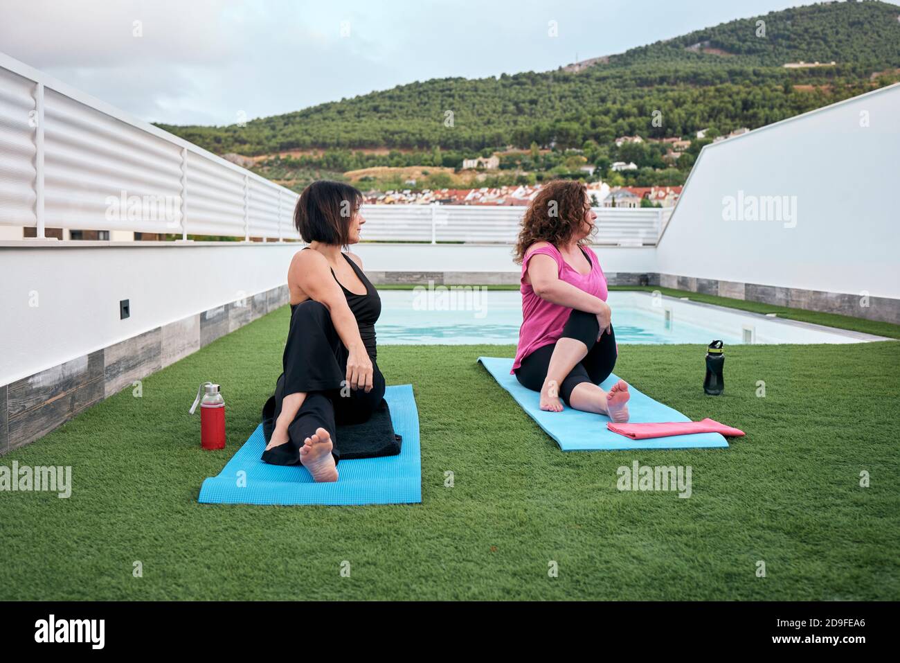 Due donne praticano lo yoga sulla terrazza della casa, la postura Marichi Foto Stock