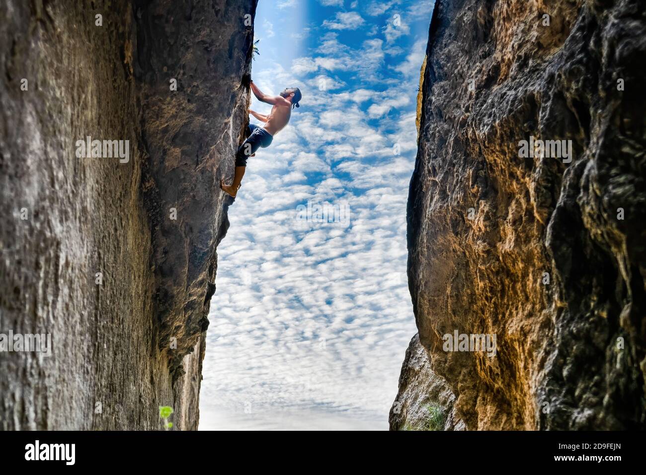 Giovane uomo libero solo arrampicata su una parete verticale senza corda e tra due pareti Foto Stock