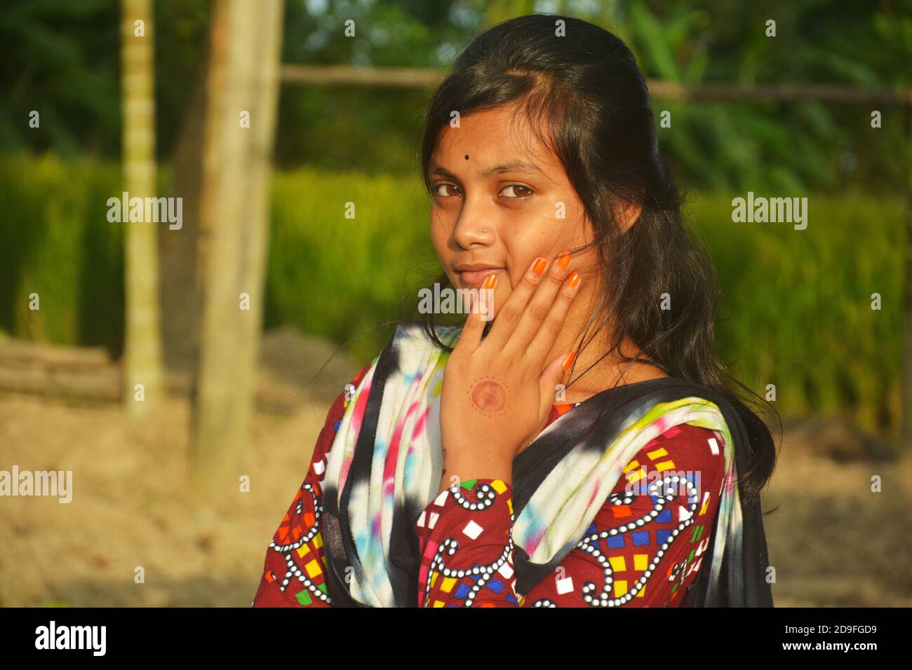 Primo piano di una ragazza indiana bengalese adolescente con lunghi capelli scuri indossare tradizionale abito salwar kameez in campo agricolo, messa a fuoco selettiva Foto Stock