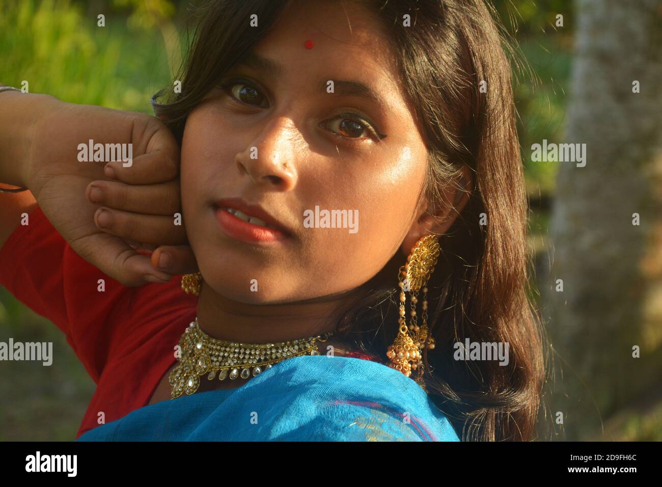 Primo piano di una ragazza adolescente indiana che indossa sari, collana dorata e bindi sulla fronte con lunghi capelli scuri, messa a fuoco selettiva Foto Stock