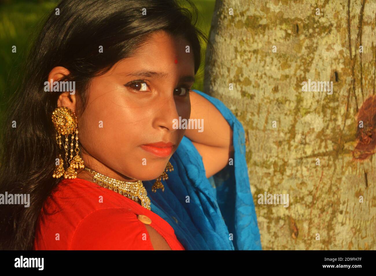 Primo piano di una ragazza adolescente indiana che indossa sari, collana dorata e bindi sulla fronte con lunghi capelli scuri, messa a fuoco selettiva Foto Stock