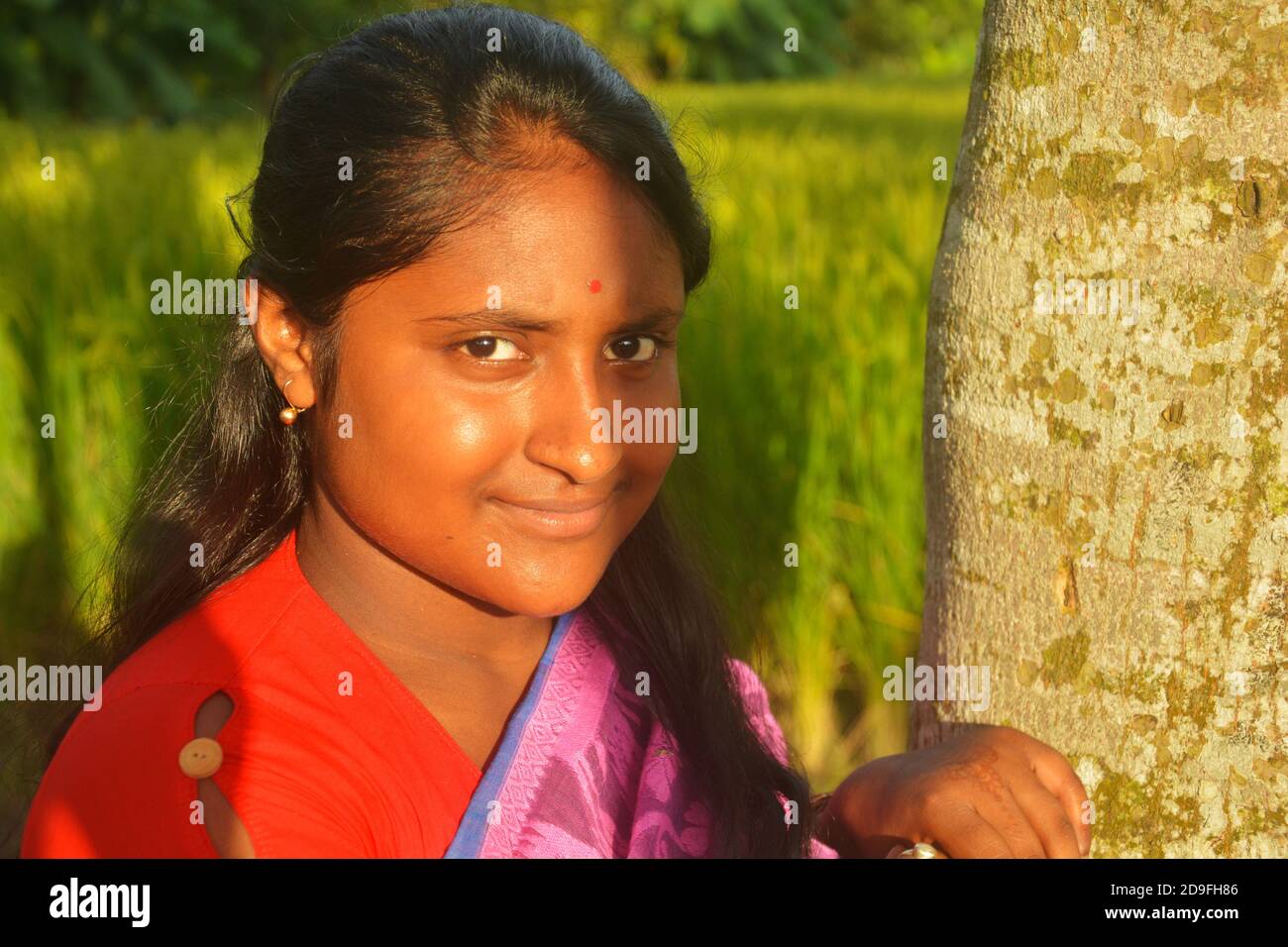 Primo piano di una ragazza adolescente indiana che indossa sari, orecchini dorati e bindi sulla fronte con lunghi capelli scuri, messa a fuoco selettiva Foto Stock