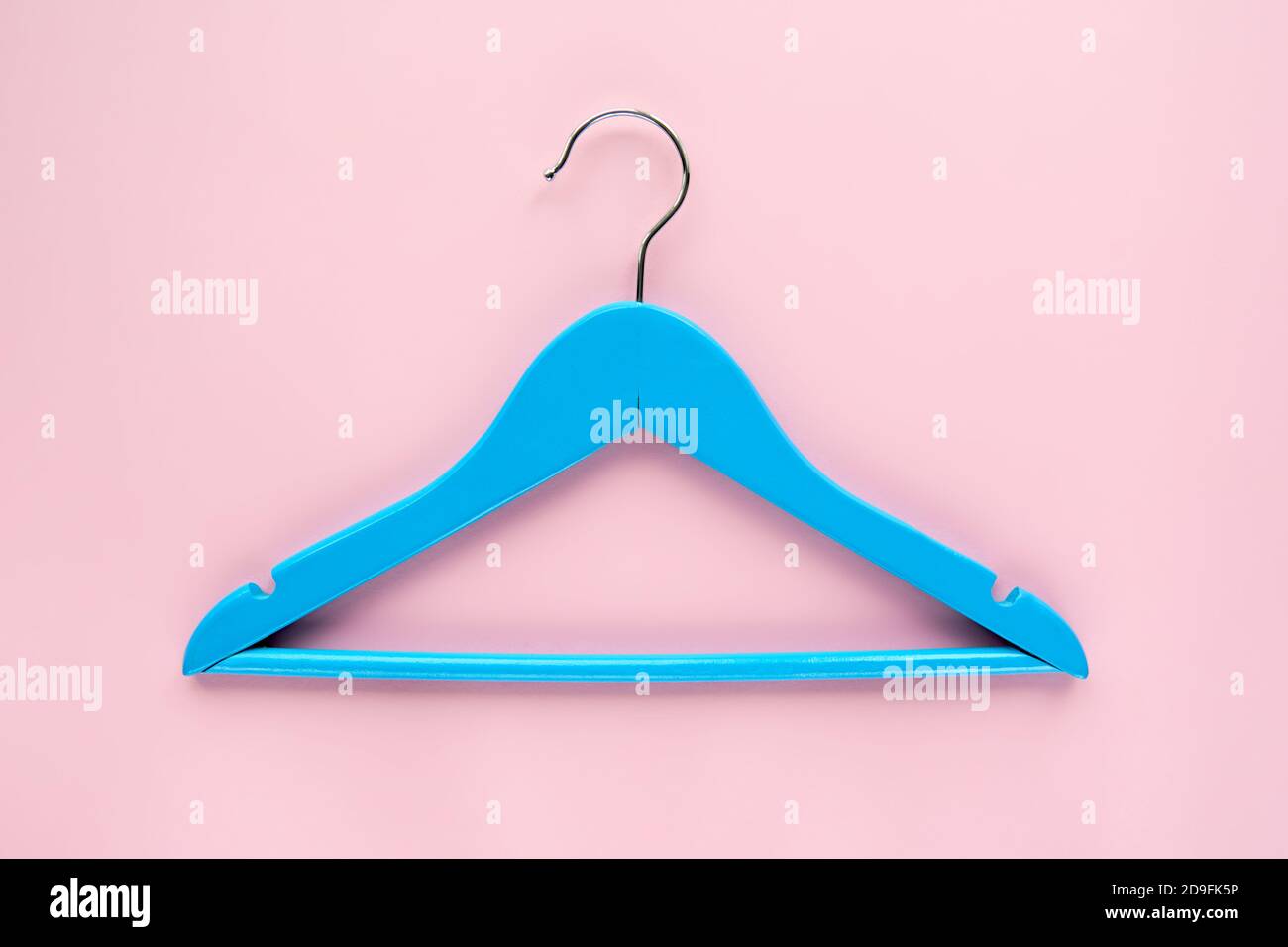 Appendiabiti in legno blu con etichetta di carta nera isolata su sfondo di carta rosa. Etichetta di abbigliamento, etichetta modello mockup vuoto, per posizionare il tuo disegno. Nero Foto Stock