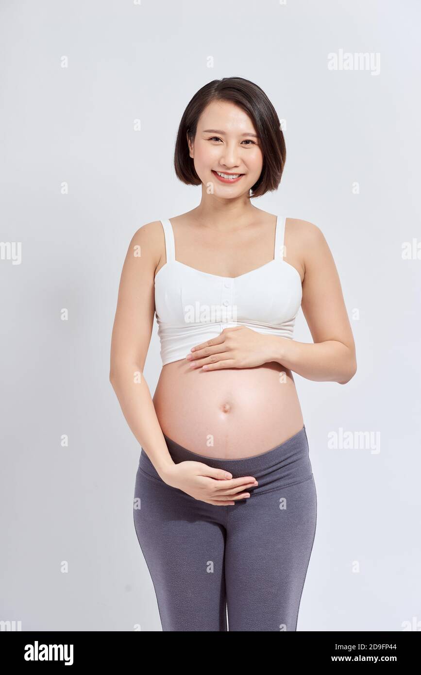 Una bella donna asiatica in piedi che tocca il suo ventre. Concetto di gravidanza e aspettativa Foto Stock