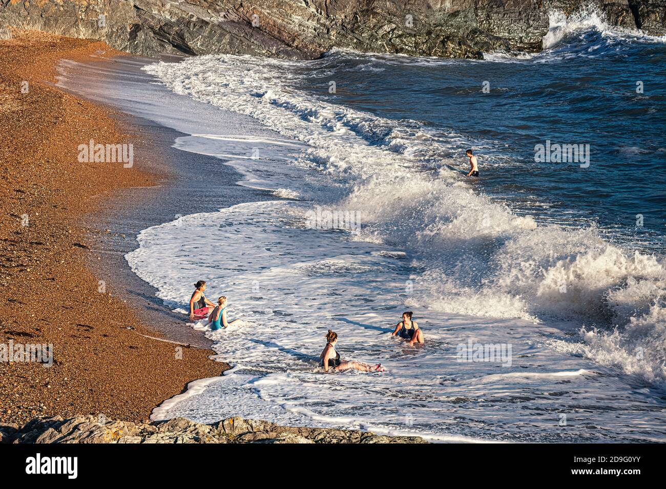 Vita quotidiana. Gruppo di donne che si siedono sulla spiaggia della città e che si divertono con le onde Foto Stock