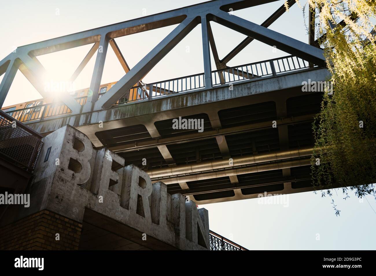 sole che splende attraverso il ponte ferroviario Foto Stock