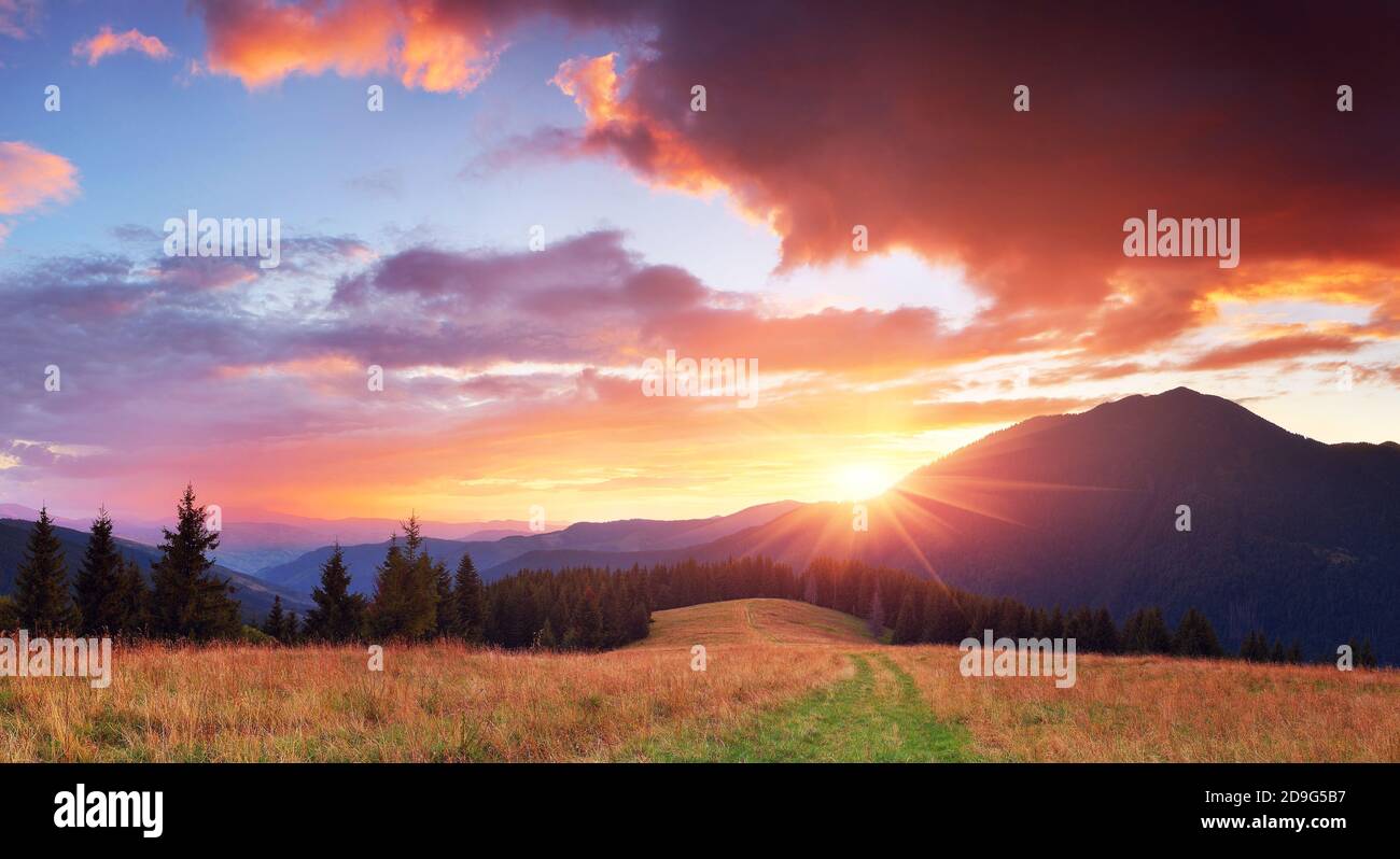 Panorama delle montagne con un bellissimo tramonto e il sole con raggi Foto Stock