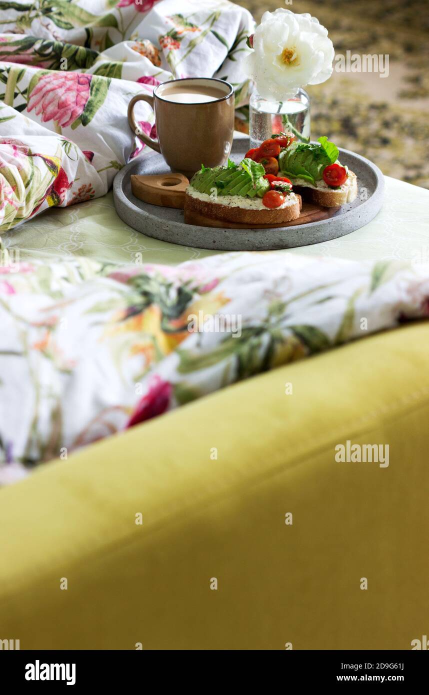 Prima colazione di panini con formaggio di cottage, avocado, pomodori e caffè, servita a letto. Foto Stock