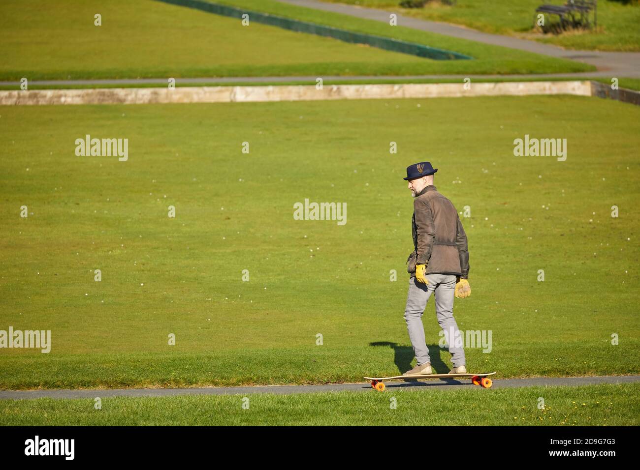 Autunno al Southport King's Gardens un uomo maturo skateboard intorno i percorsi Foto Stock