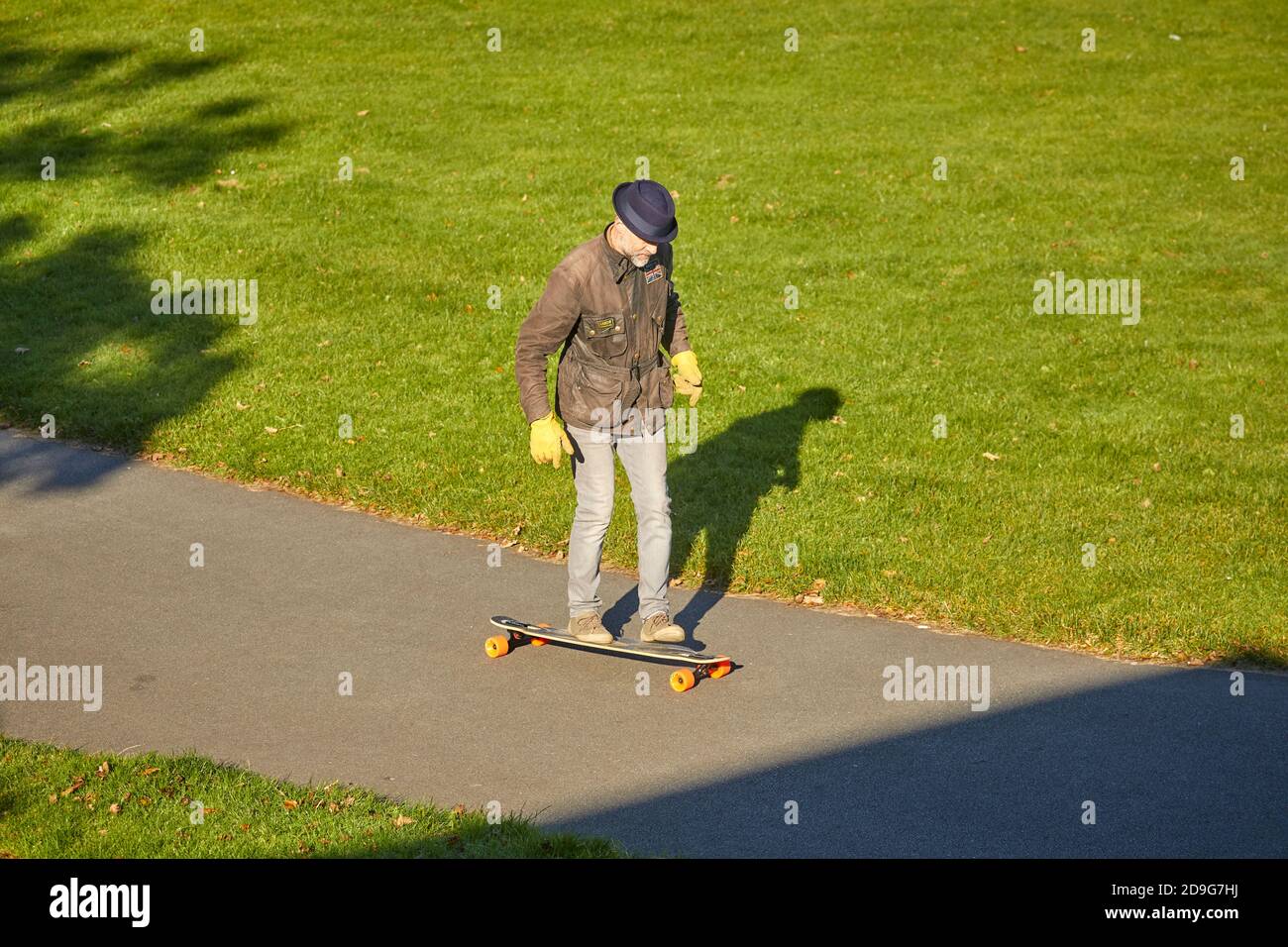 Autunno al Southport King's Gardens un uomo maturo skateboard intorno i percorsi Foto Stock