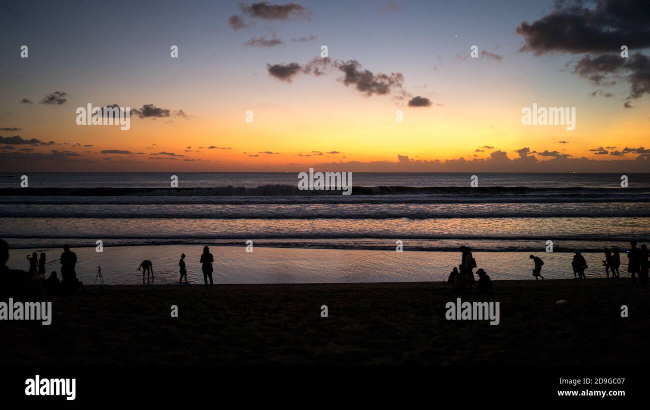Silhouette di persone sulla spiaggia al tramonto, ora d'oro sul mare, calme e tranquille vibrazioni, tempo di famiglia sulla spiaggia Foto Stock