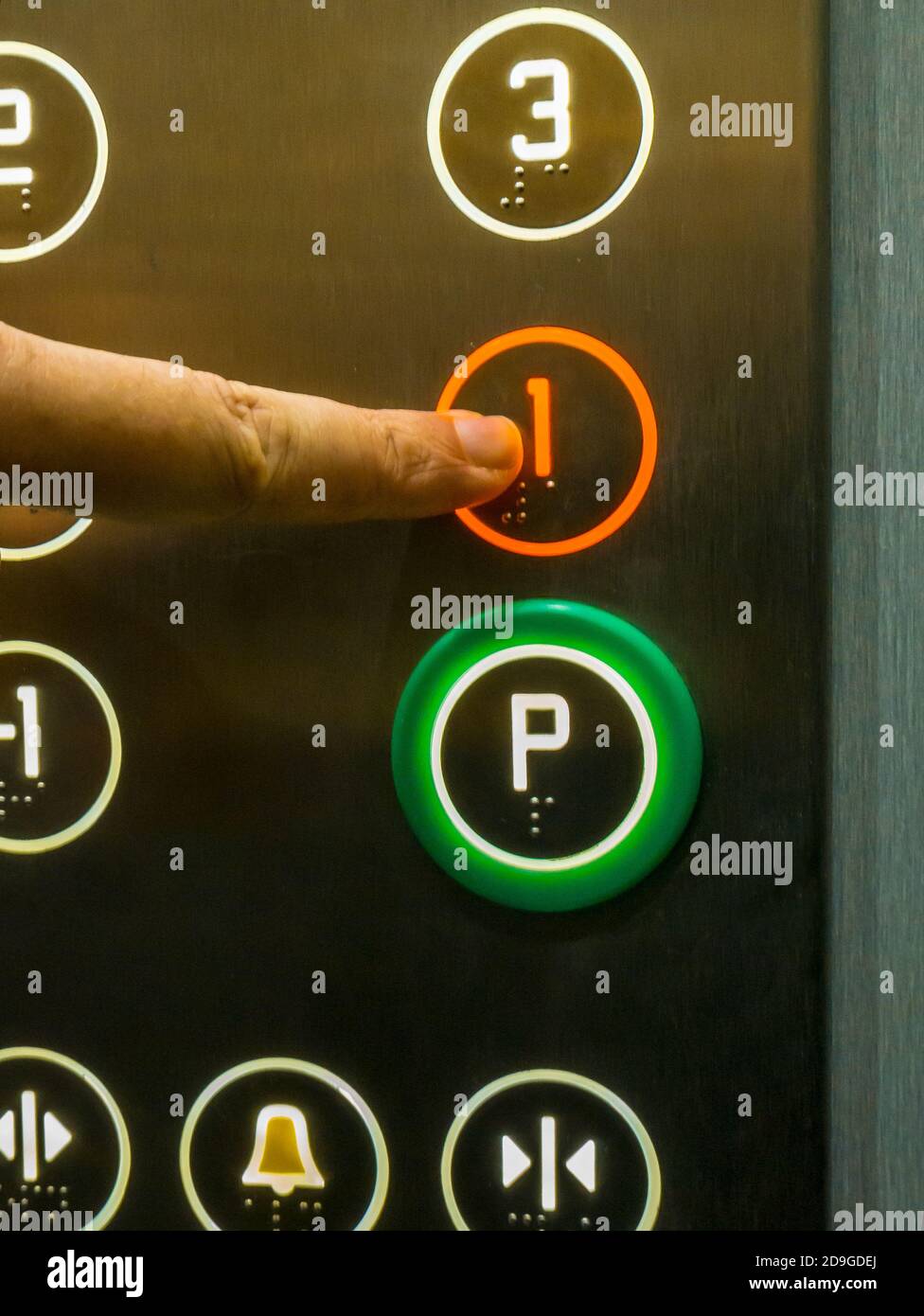 Mano umana premendo il pulsante del primo piano nell'ascensore Foto Stock
