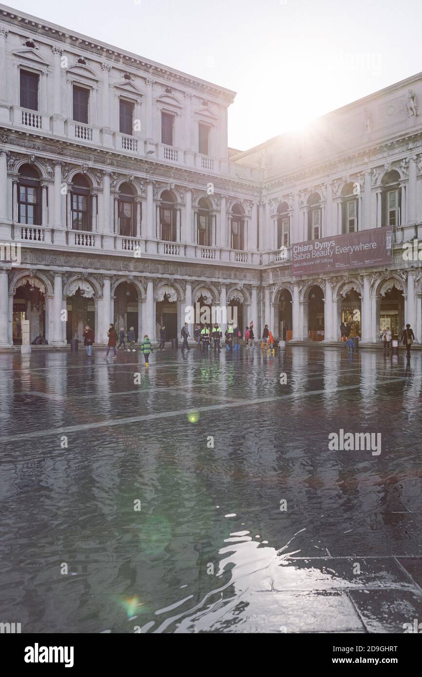 Turisti che scattano fotografie in Piazza San Marco con alta marea, acqua alta, con vista sulla San Marco Procuratie Foto Stock