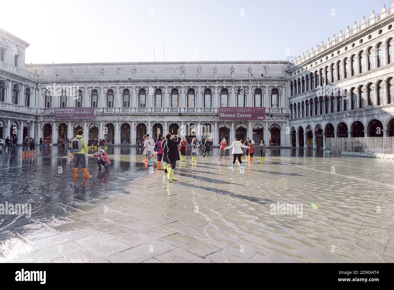 Turisti che scattano fotografie in Piazza San Marco con alta marea, acqua alta, con vista sulla San Marco Procuratie Foto Stock