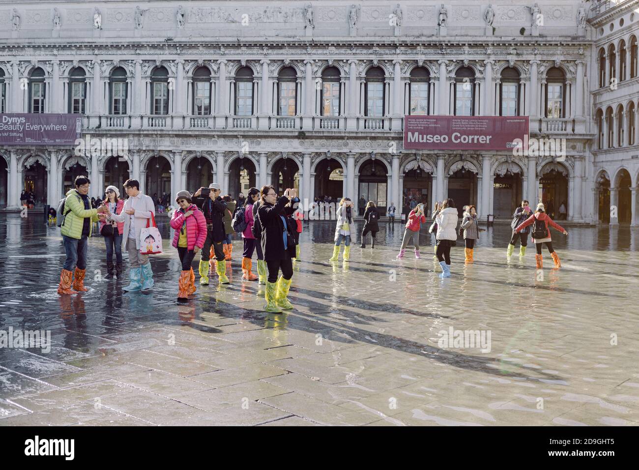 Turisti che scattano fotografie in Piazza San Marco con alta marea, acqua alta, con vista sulla San Marco Procuratie Foto Stock