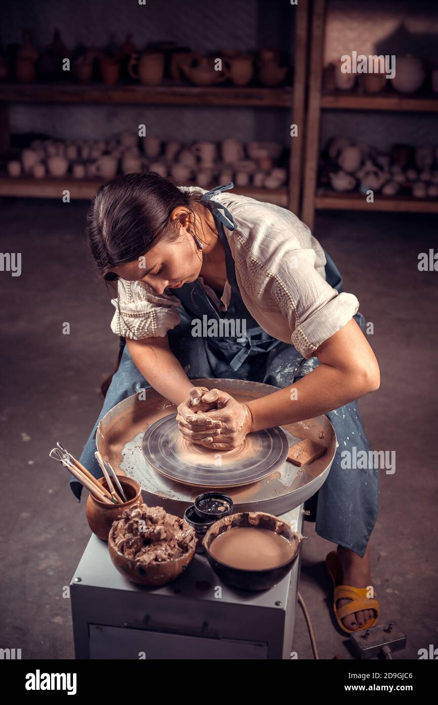 Donna di ceramica di charme che fa pentola di ceramica sulla ruota di ceramica . Laboratorio di ceramica. Foto Stock