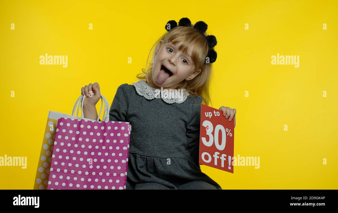 Bambina che mostra fino a 30 per cento di sconto iscrizione segno e shopping borse. Teen allievo sorridente, guardando soddisfatto con i prezzi bassi, lo shopping su Black Friday, Natale o Capodanno Foto Stock