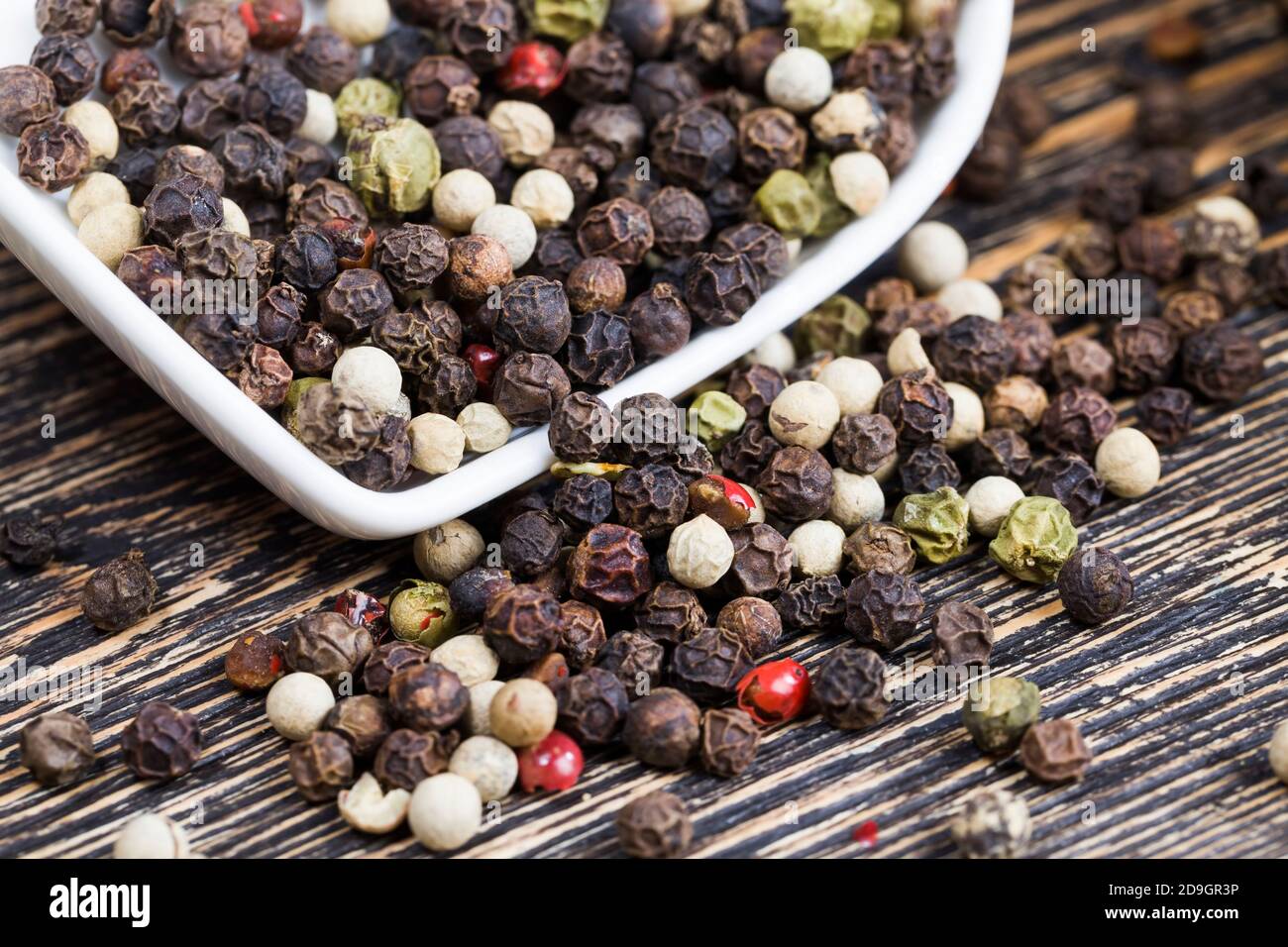 pepe di piselli neri su un vecchio tavolo di legno Foto Stock