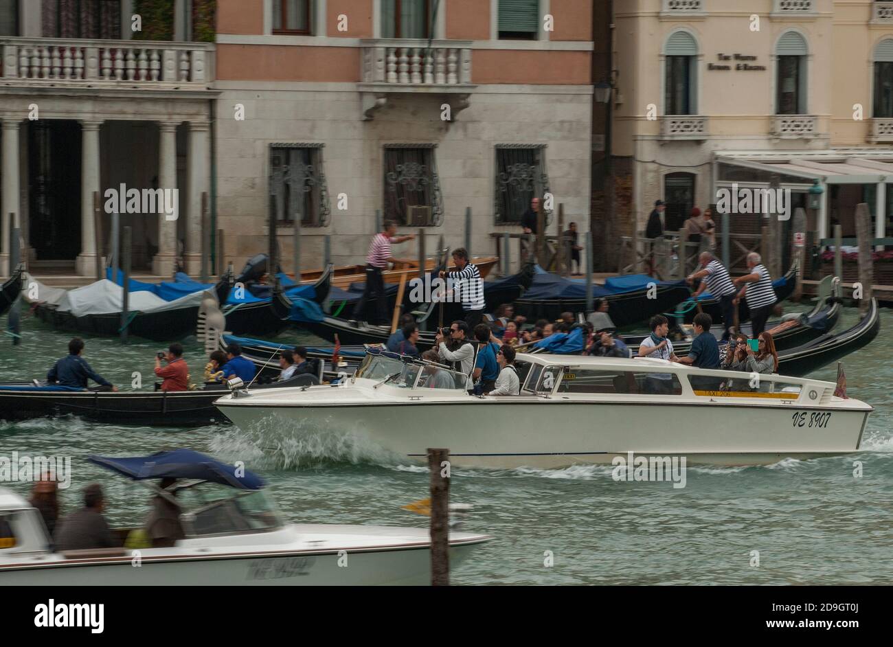 Una barca porta turisti stranieri passando altre barche e gondola che trasportano turisti sul canale Granale affollato a Venezia, Italia. Foto Stock