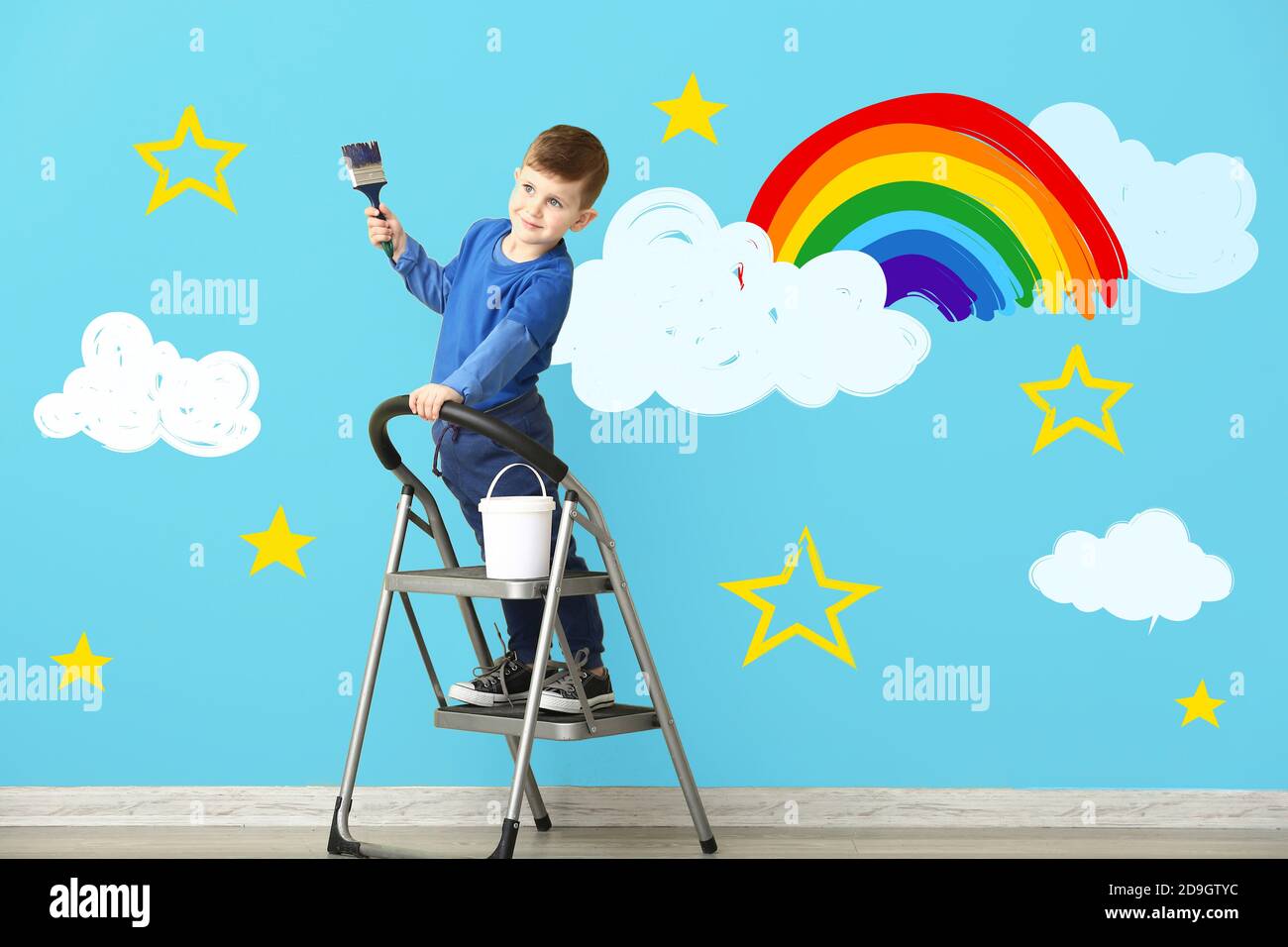 Carino ragazzo dipinto arcobaleno e nuvole sulla parete Foto Stock