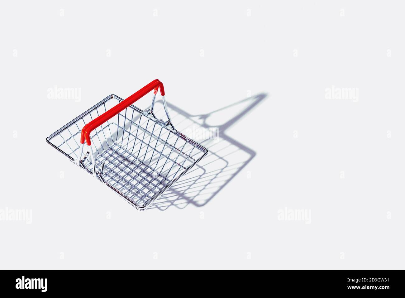 Cestino vuoto in metallo con maniglie rosse su sfondo grigio. Salario vivente. Ombre dure. Foto Stock