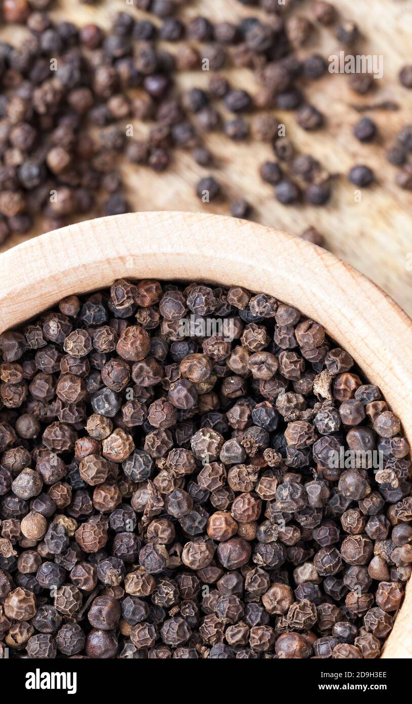 pepe nero speziato sparso su un vecchio tavolo di legno Foto Stock
