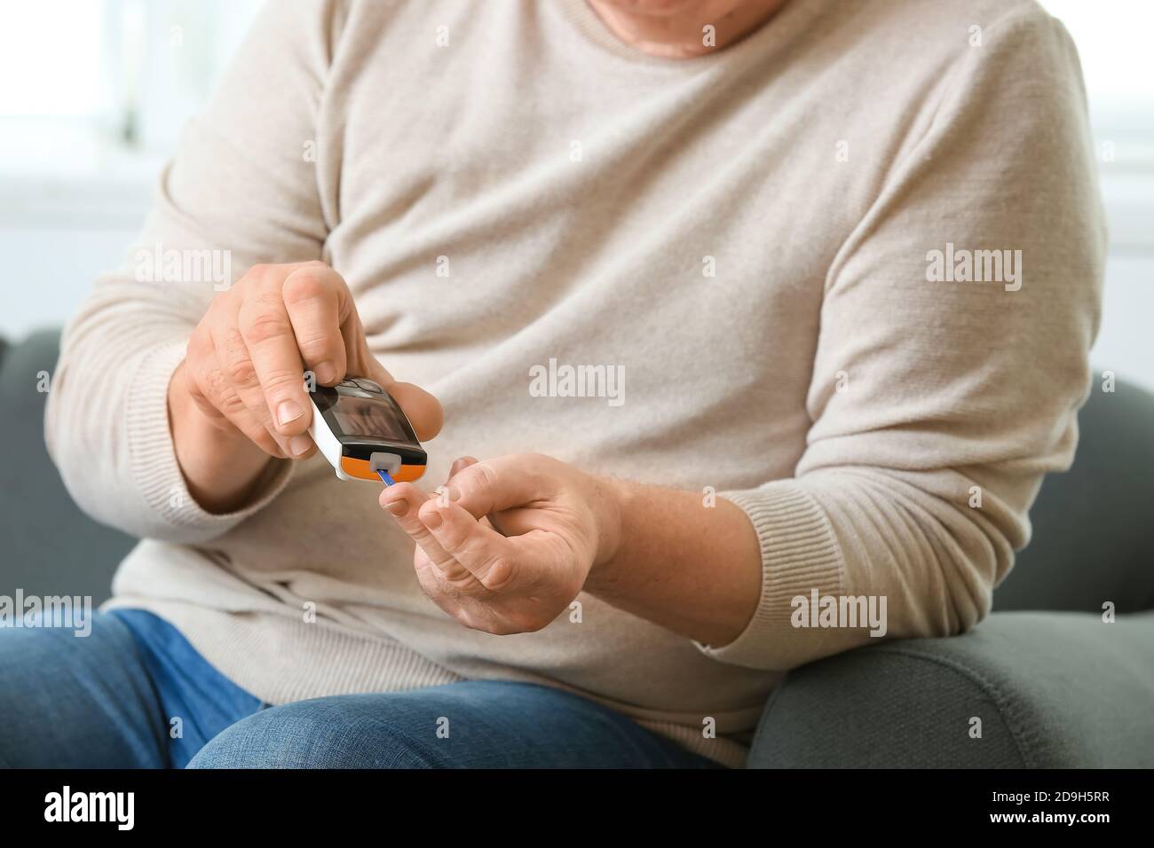 Uomo diabetico anziano che controlla il livello di zucchero nel sangue a casa Foto Stock