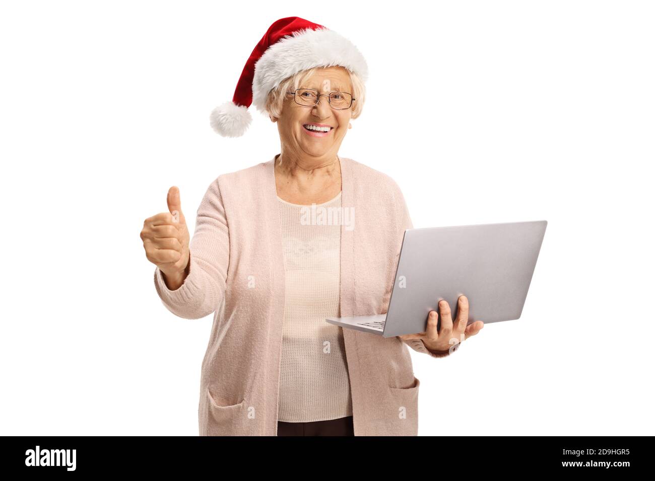Donna anziana felice in possesso di un computer portatile che indossa una santa cappello e mostrare i pollici su isolato su sfondo bianco Foto Stock