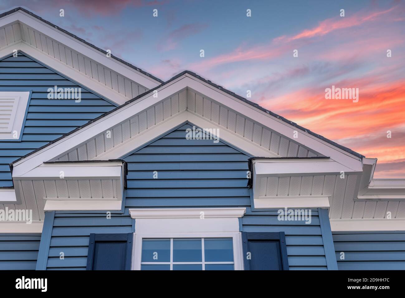 A forma di triangolo decorativo gable con soffit coloniale bianco e fascia su un vinile orizzontale blu che sorsegge moderna casa americana con dram colorata Foto Stock