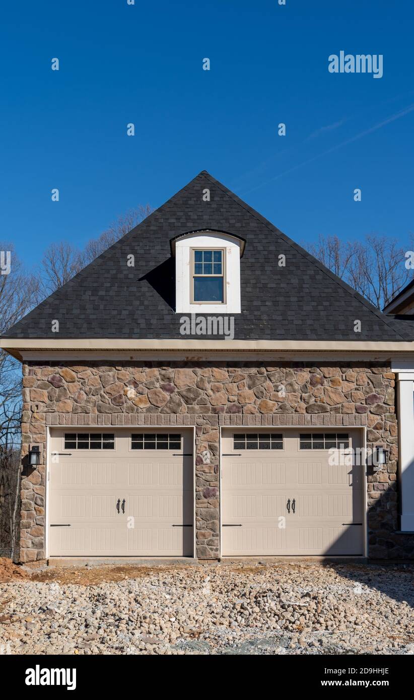 Due porta singola garage incorniciato con pietra architettonica per aggiungere accento, con finestre luce di specchio diviso muntins griglie hip tetto con dormer wi Foto Stock