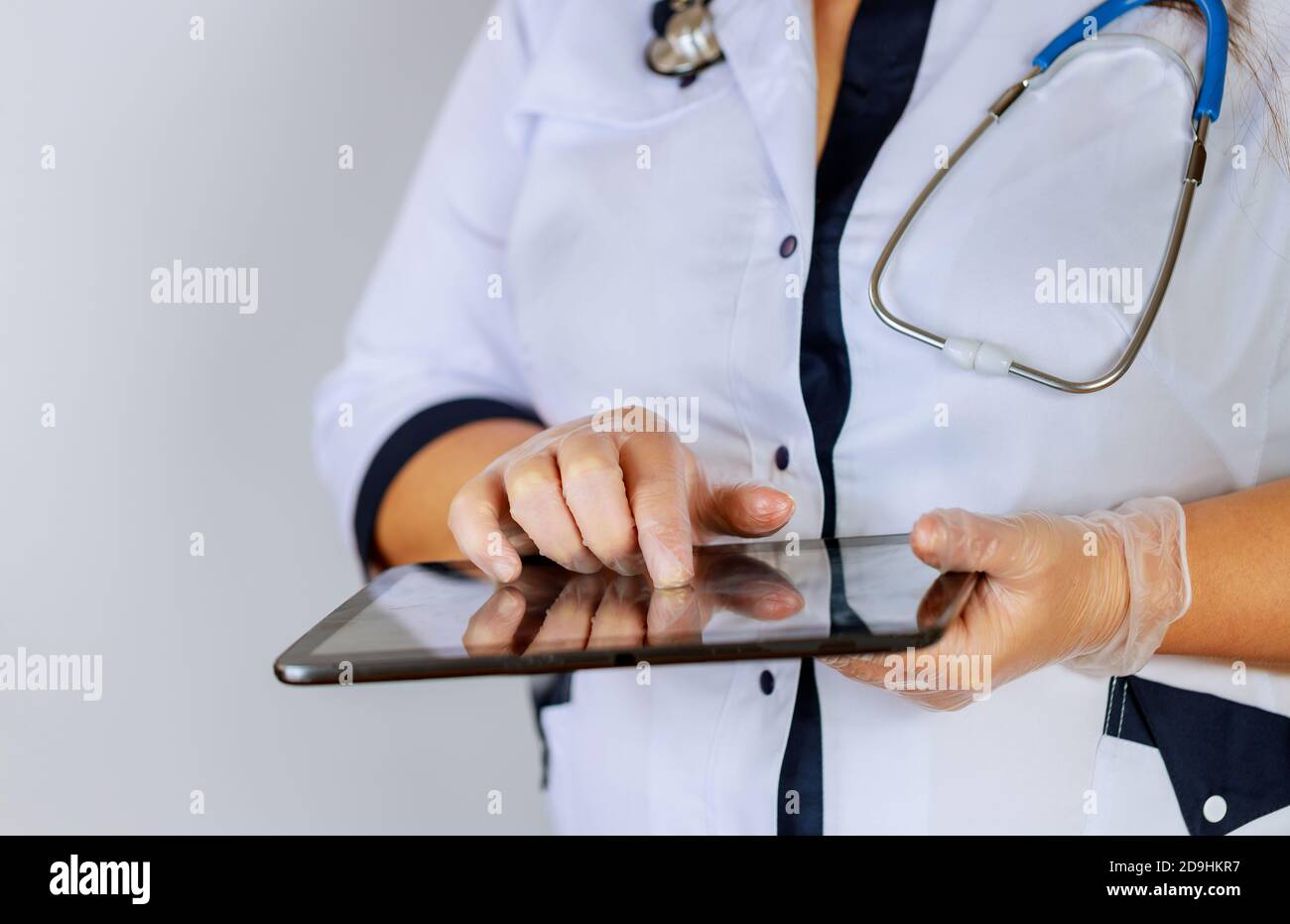 Medico femminile che usa un tablet digitale mentre si sta in piedi vicino alla scrivania presso la clinica di emergenza medico ospedaliero al lavoro. Foto Stock