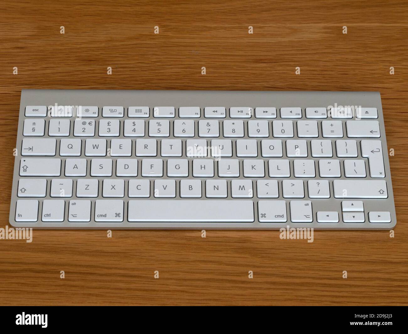 Computer Bluetooth wireless Apple Magic tastiera QWERTY inglese inglese con tasti bianchi e corpo in alluminio anodizzato argentato su sfondo in legno. Foto Stock