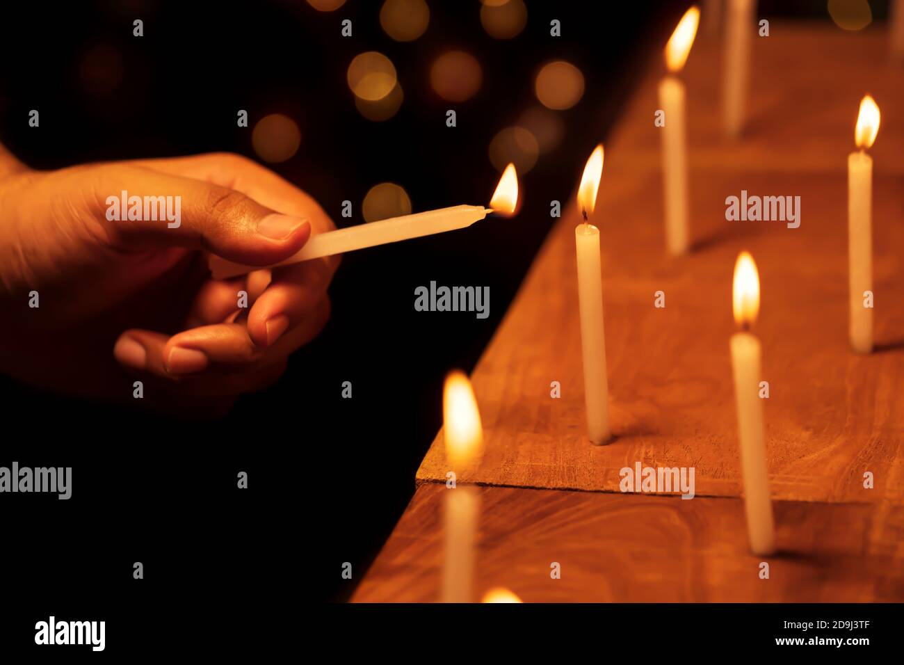 Mano maschile che illumina o illumina le candele nella notte di Diwali al tempio, chiesa. Immagine di sfondo per decorazioni natalizie, feste, striscioni. Foto Stock