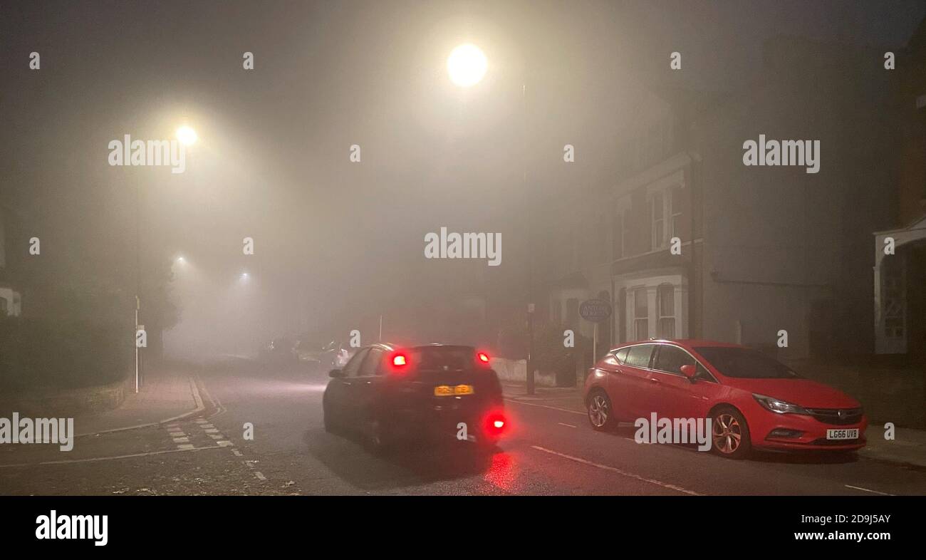 Un automobilista attraversa una fitta nebbia lungo una strada a Kew, a ovest di Londra. I previsori si aspettano che le condizioni avverse si sollevino più tardi al mattino, prima di tornare questa sera. Foto Stock