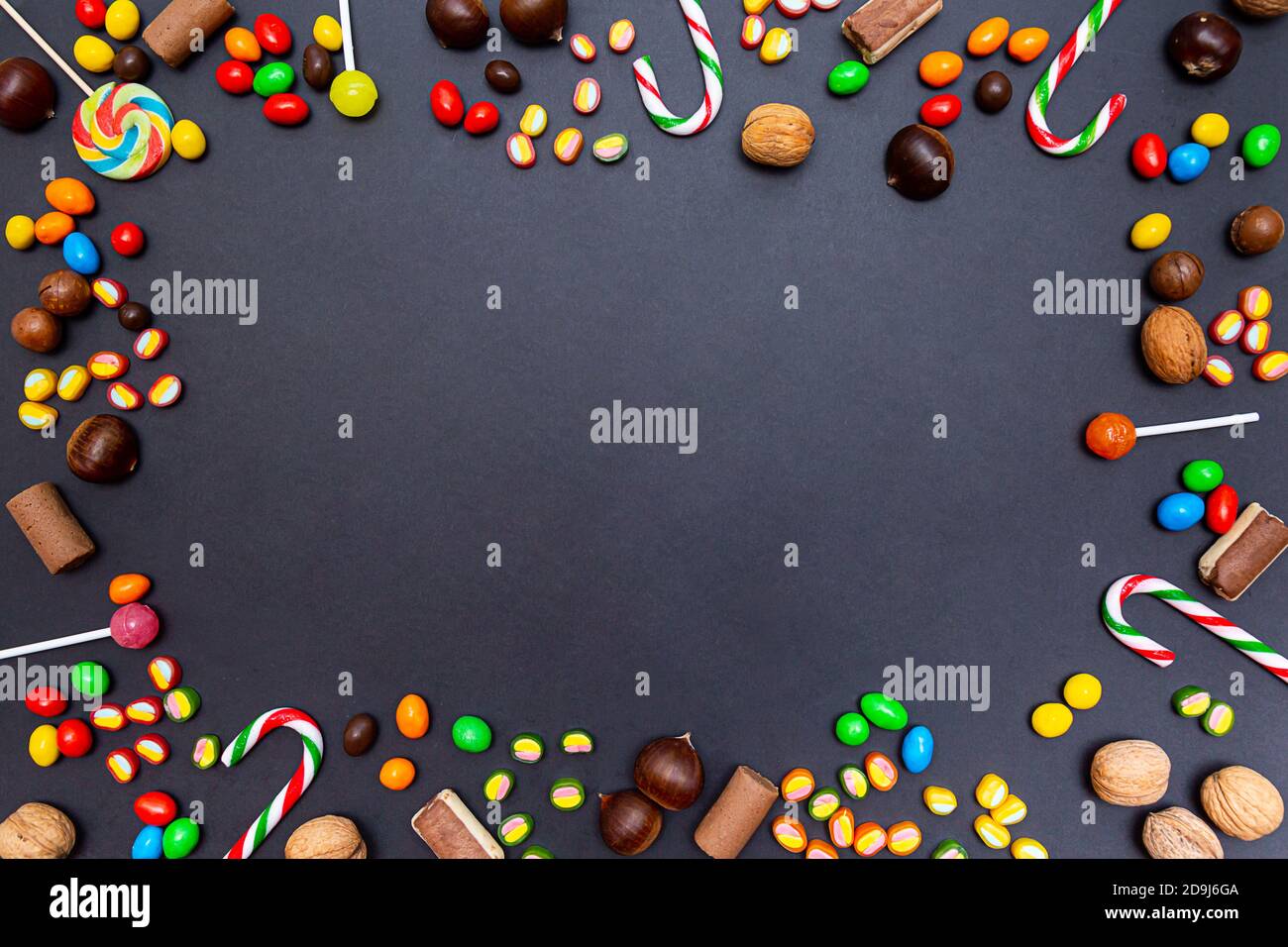 Vari dolci, leccarpe, caramelle, marmellate, noci, castagne su fondo nero. Composizione festiva. Cibo sfondo Foto Stock